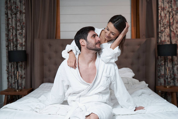 Man on bed turning face to his smiling wife - Foto, Bild