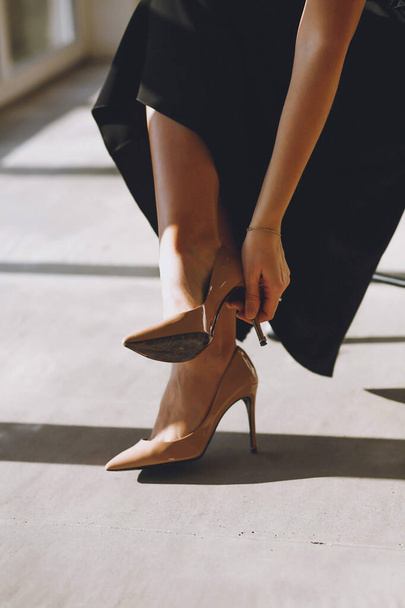 De cerca la foto de la mujer quitándose los zapatos de tacón alto interior. Hermosas piernas de mujer. Bueno para papel pintado o revista de impresión - Foto, imagen