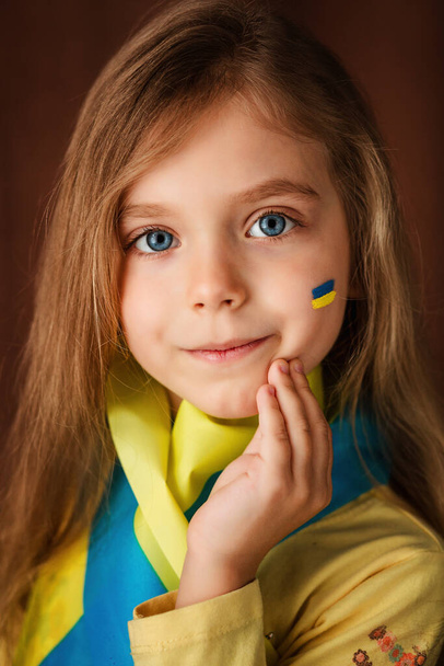 Portrait of a little girl with the Ukrainian flag painted on her face - Foto, afbeelding