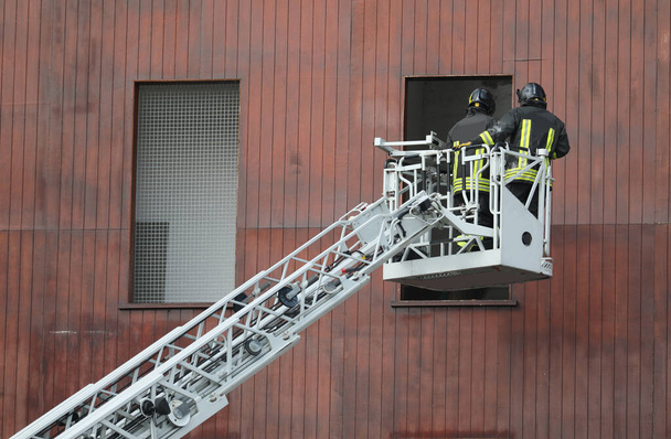消防署の消防士ははしご車のバスケットで窓からアクセスできます - 写真・画像