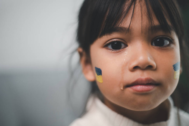 Lapsi Ukrainan lipun kanssa itkee. Suru kaipaa toivoa. Lasten kyyneleet sodasta. Siviilien evakuointi. Vapaus Ukrainaan - Valokuva, kuva