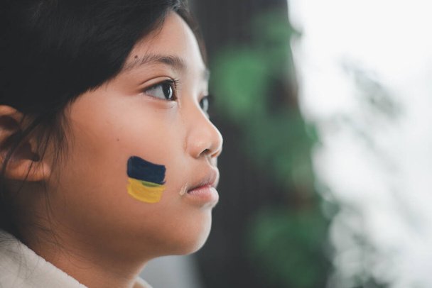 Ένα παιδί με τη σημαία της Ουκρανίας κλαίει. Θλίψη λαχτάρα ελπίδα. Τα δάκρυα των παιδιών από τον πόλεμο. Εκκένωση πολιτών. Ελευθερία στην Ουκρανία - Φωτογραφία, εικόνα