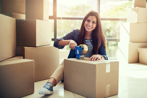 I cant wait to move into my dream home soon. Portrait of a young woman packing boxes while moving house. - Zdjęcie, obraz