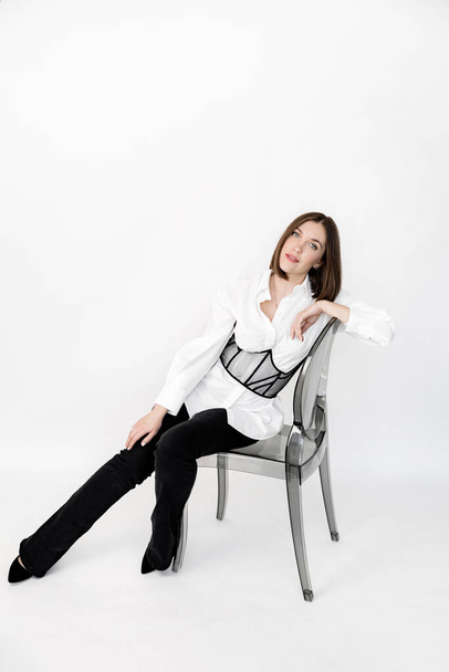 beautiful brunette woman in a white shirt and black trousers posing in studio - Foto, imagen