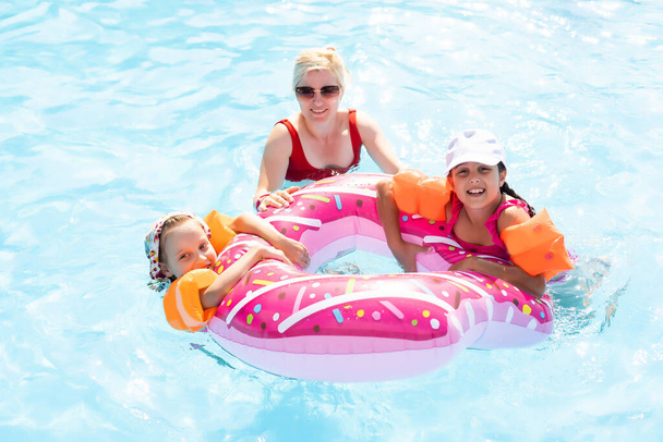 Glückliche Familie spielt im blauen Wasser des Swimmingpools in einem tropischen Resort am Meer. Sommerferienkonzept. - Foto, Bild
