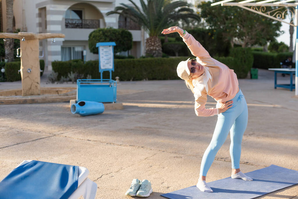 fitness, sport, lidé a zdravého životního stylu koncepce - žena dělat jógu v pán tance představují na rohoži pláž a bazén pozadí. - Fotografie, Obrázek