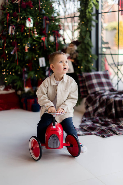 little boy playing with toy car at home near Christmas tree - Zdjęcie, obraz