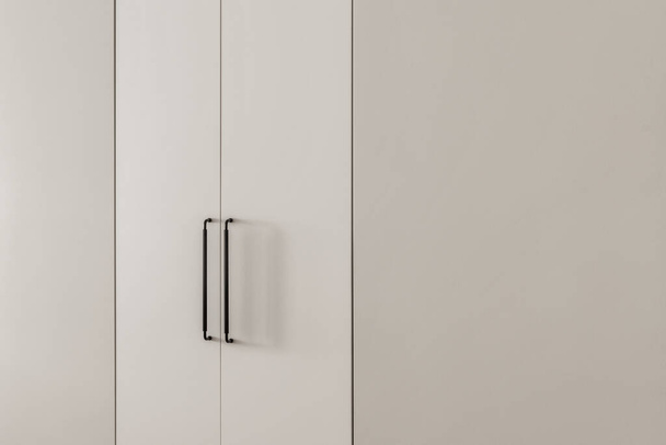 Built-in wardrobe with light grey doors and black handles. Minimal interior concept - Fotoğraf, Görsel
