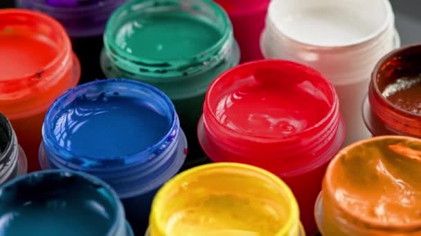 loopable rotating close-up background of opened small gouache paint jars - Materiał filmowy, wideo