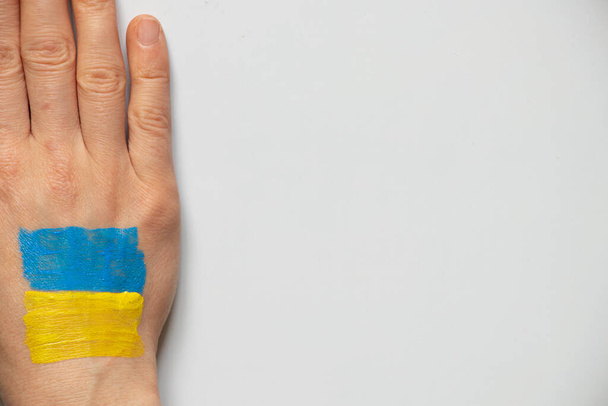 Η σημαία της Ουκρανίας σχεδιάζεται από το χέρι ενός ουκρανού κοριτσιού σε λευκό φόντο, να σταματήσει τον πόλεμο στην Ουκρανία 2022 - Φωτογραφία, εικόνα