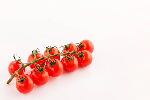 geïsoleerde kleine rode rijpe tomaten op een takje op witte achtergrond - Foto, afbeelding