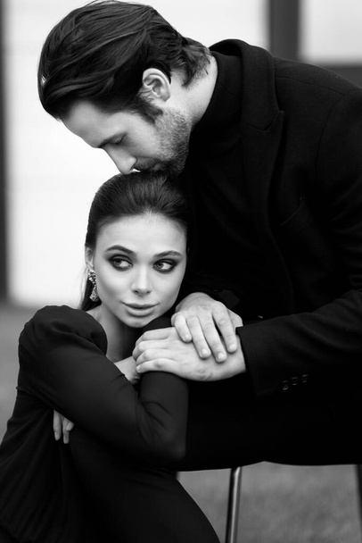 Stylish dressed caucasian couple having a photoshoot in black outfits. Beautiful young woman posing near charming beard man outdoor. - Φωτογραφία, εικόνα