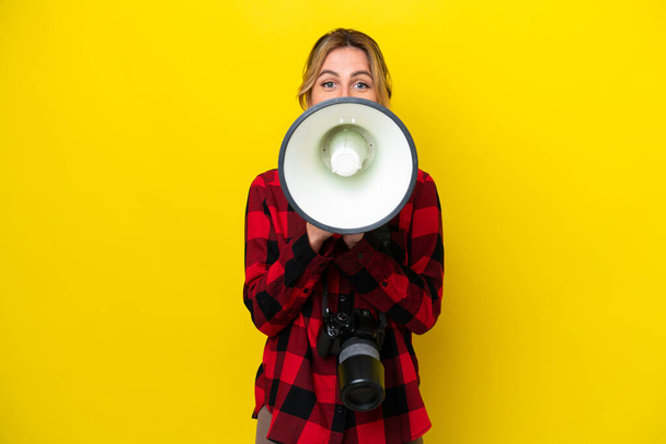 Uruguayan photographer woman isolated on yellow background shouting through a megaphone - Photo, Image