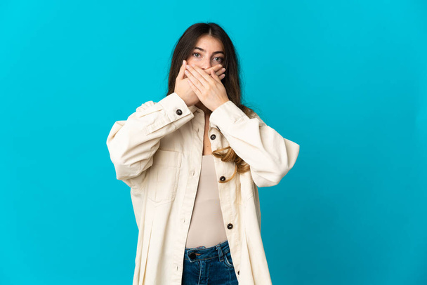 Young caucasian woman isolated on blue background covering mouth with hands - Foto, Imagem