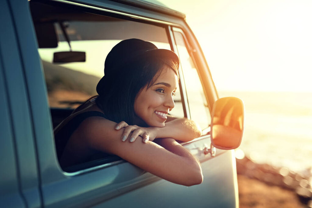 Slowing it down this summer. Shot of a young woman enjoying a relaxing roadtrip. - 写真・画像