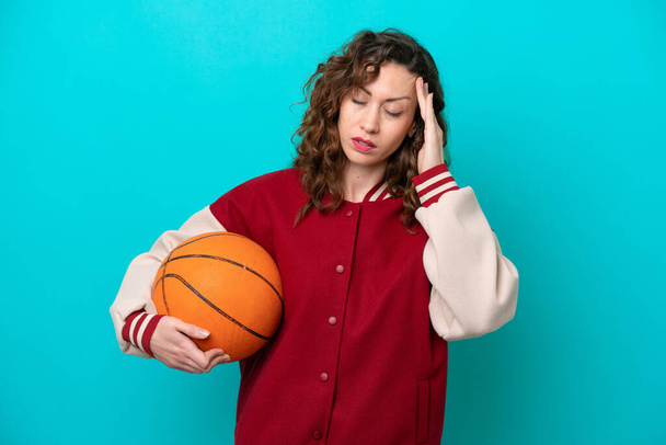 Young caucasian basketball player woman isolated on blue background with headache - Foto, Bild