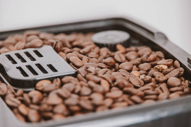brown large coffee beans in a coffee machine in background closeup - Fotó, kép