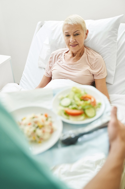 Paziente anziana che fissa la persona, portando la colazione in ospedale - Foto, immagini