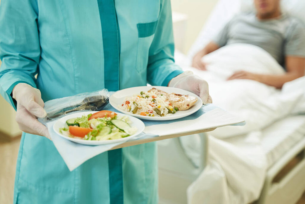 Медична особа тримає лоток з їжею в лікарні
 - Фото, зображення