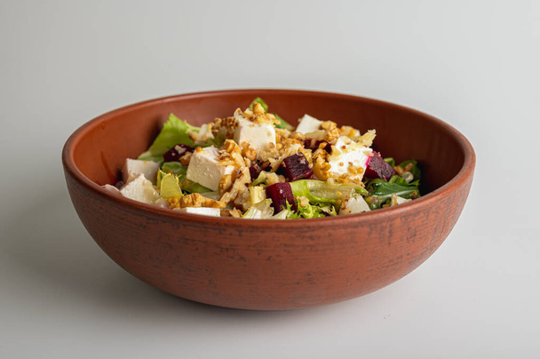 Spring salad with chicken fillet, feta cubes, breadcrumbs, quail eggs, on a clay plate isolated on a white background. Selective focus. The concept of delicious spring salads - Photo, Image