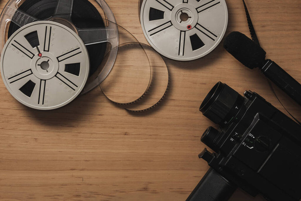 Old 8 mm video camera with film reels on wooden background. Copy space. Selective focus. - Photo, image