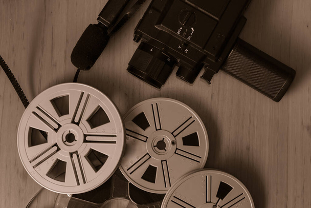 Old 8 mm video camera with film reels on wooden background. Copy space. Selective focus. - Zdjęcie, obraz