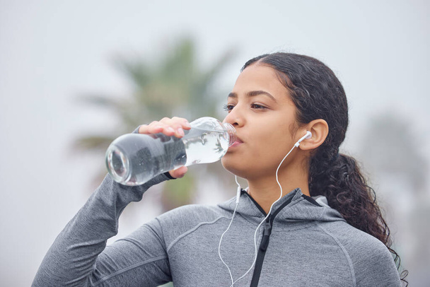Non dimenticare di mantenerti idratato. Girato di una giovane donna che beve acqua mentre si esercita in natura. - Foto, immagini