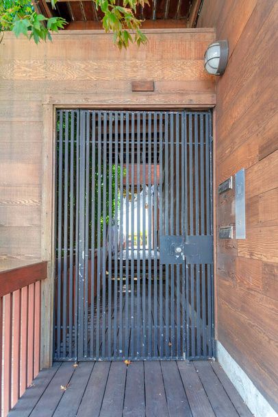 Wrought iron gate with wood planks walls and pathway at San Francisco, California. Entrance of a house with railings on the left across the wooden wall with two wall-mounted mailboxes on the right. - Photo, Image