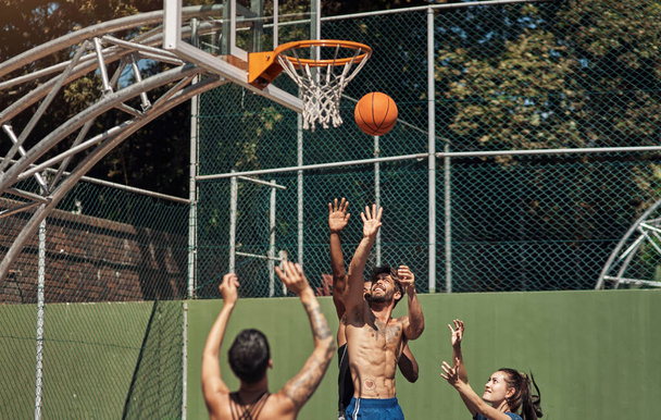 Will he make the shot. Shot of a group of sporty young people playing basketball on a sports court. - Photo, image