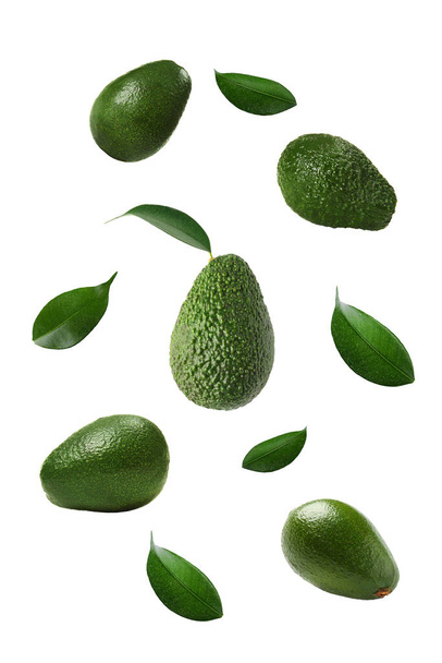 Fresh flying avocados and green leaves isolated on white - Foto, immagini