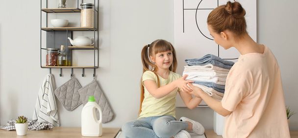 Woman and her cute little daughter doing laundry at home. Banner for design - Фото, изображение