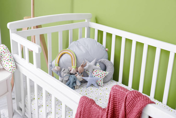 Comfy crib with soft toys near color wall - Φωτογραφία, εικόνα