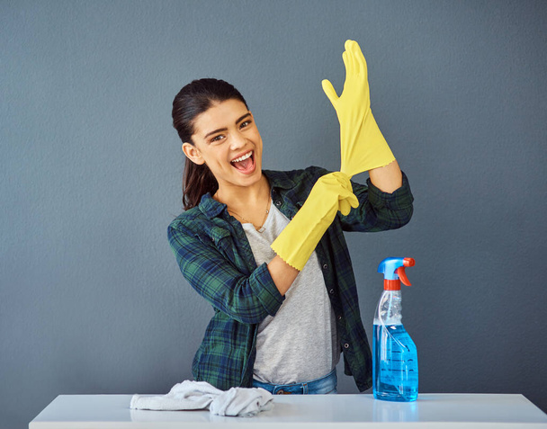 I never clean without my rubber gloves. Studio portrait of an attractive young woman putting on her rubber gloves to do some spring cleaning. - Photo, Image