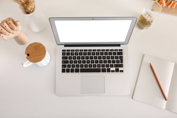 Modern laptop, csésze, notebook és stílusos dekoráció könnyű asztalon - Fotó, kép