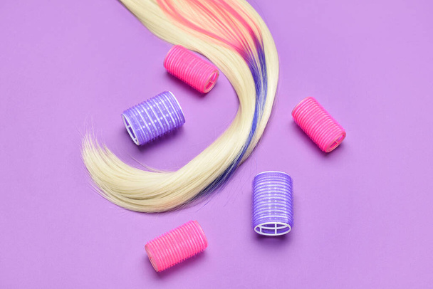 Long hair strand and curlers on color background - 写真・画像