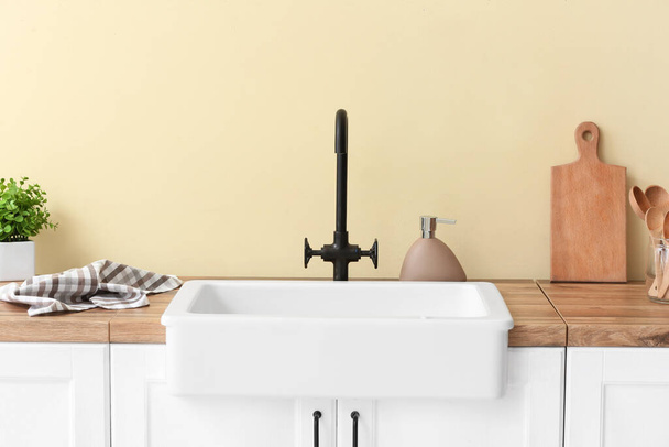 Лічильник з кухонним посудом і керамічною раковиною біля кольорової стіни
 - Фото, зображення
