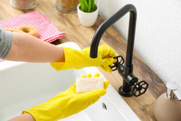 Γυναίκα με λαστιχένια γάντια που βρέχει σαπούνι στο νεροχύτη, κοντινό πλάνο - Φωτογραφία, εικόνα