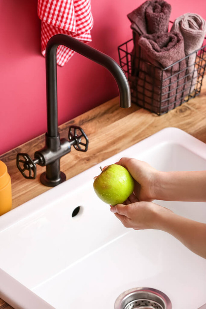 Woman washing fresh green apple in modern sink, closeup - Fotó, kép