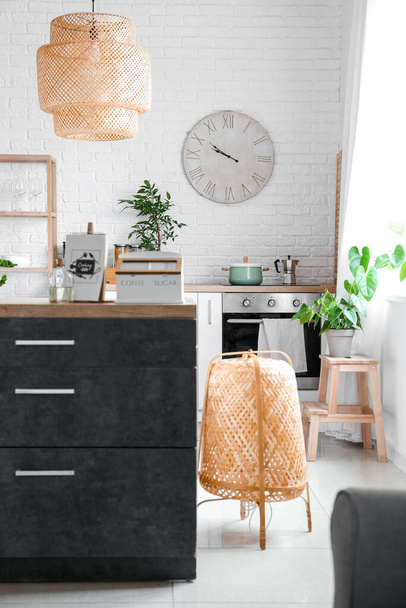Interior of modern kitchen with counters, houseplants and clock - Foto, afbeelding