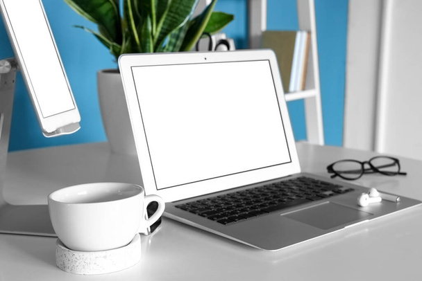 laptop moderno, fones de ouvido e xícara na mesa, close-up - Foto, Imagem