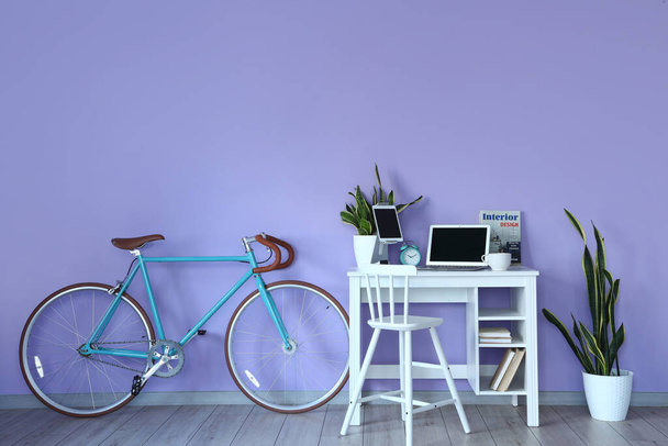Комфортне робоче місце і велосипед біля кольорової стіни в інтер'єрі кімнати
 - Фото, зображення