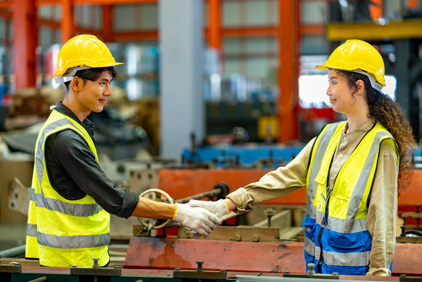 El equipo de trabajadores industriales asiáticos está estrechando la mano mientras trabaja dentro de la fábrica de techos para la industria de acuerdos y seguridad - Foto, Imagen