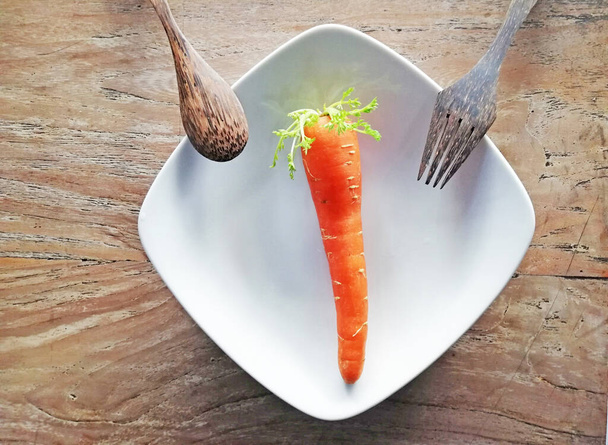 Growing carrots,placed on brown wooden background - 写真・画像