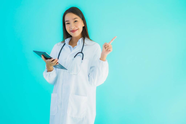 Портрет красива молода азіатка-лікарка зі стетоскопом і смарт-планшетом для використання в лікарні і клініці на синьому ізольованому фоні
 - Фото, зображення
