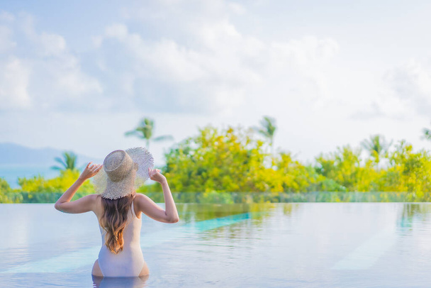 Portrait belle jeune femme asiatique profiter autour de la piscine extérieure avec vue sur l'océan de mer en voyage vacances - Photo, image