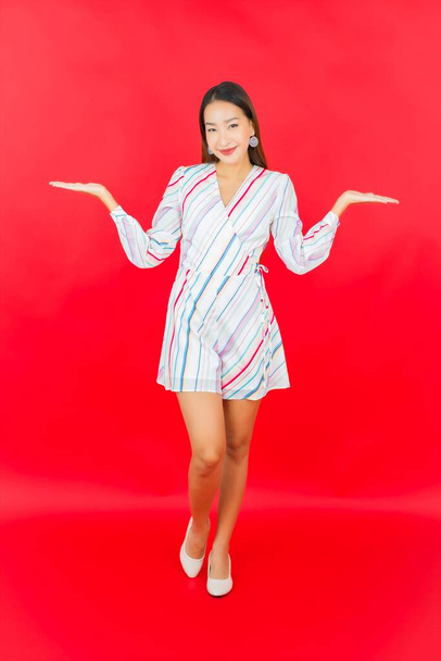 Retrato hermosa joven asiática mujer sonrisa con muchos acción en rojo fondo - Foto, Imagen
