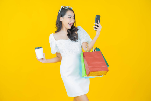 Portrait beautiful young asian woman smile with shopping bag on color background - Foto, imagen