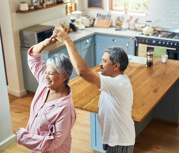 Ik kom een beetje in de ochtend dansen. Opname van een vrolijk bejaard echtpaar dat overdag samen in de keuken danst. - Foto, afbeelding
