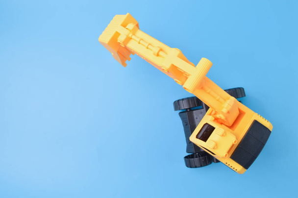 Construction digger tractor toy isolated on a blue background - Foto, imagen