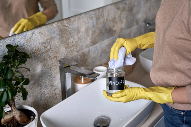 Nierozpoznawalna kobieta sprzątająca łazienkę z octem - Zdjęcie, obraz
